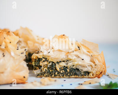 Torta greca spanakopita sul tavolo blu con DOF poco profondo. Fetta di Vegetariano o Vegano Spanakopita Torta di Spinaci con copia spazio. Idee e ricette per una sana pausa pranzo. Foto Stock