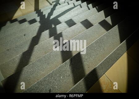 Ombra di una griglia della finestra sui gradini di una scala di una scala Foto Stock