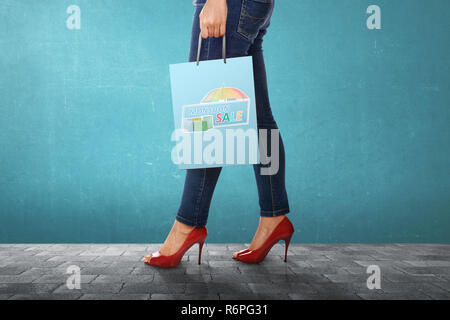 Donna che trasportano shopping bag con il monsone di segno di vendita Foto Stock