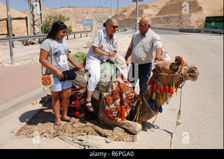 Turista femminile di essere aiutato a montare un cammello per intrattenimento ride su Israele Highway 90 allo svincolo per Qaser El Yahud in terreni sterili di una parte del paese, Foto Stock