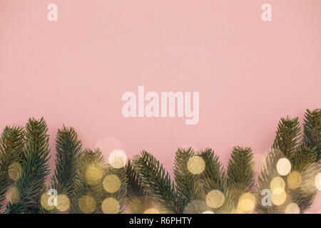 Festive Abete rami e bokeh sfocate luci fairy su uno sfondo rosa Foto Stock