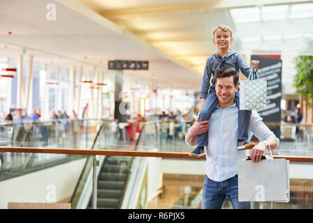 Padre porta il bambino sulle spalle mentre lo shopping in un centro commerciale Foto Stock