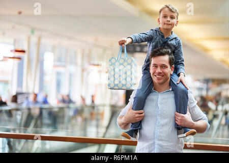 Padre shopping presso il centro commerciale porta il suo figlio sulle spalle Foto Stock