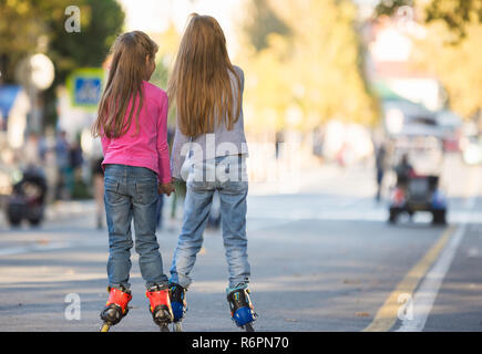 Due ragazze fidanzate roller sul mall, vista posteriore Foto Stock