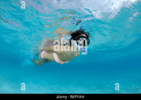 Giovane bella donna galleggia sulla superficie dell'acqua, dell'Oceano Indiano, Maldive Foto Stock