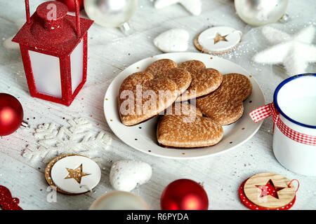 Piastra di natale con fatti in casa gingerbreads fiocchi di neve e baubles lanterna rossa su un placcati argento tabella. Foto Stock