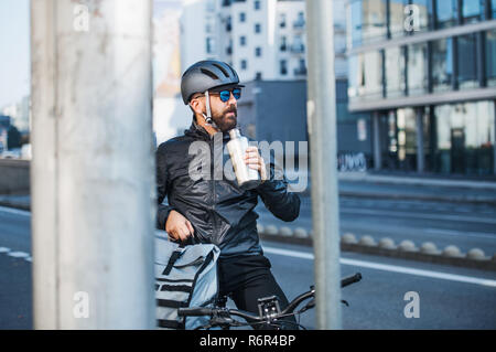 Tanga maschio corriere in appoggio quando la consegna di pacchi in città. Copia dello spazio. Foto Stock