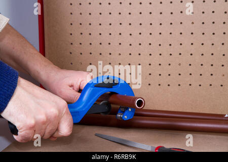 Plumber al lavoro sul suo banco di lavoro per montare i tubi Foto Stock