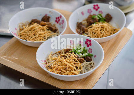 3 ciotole di Khao Soi che stile tailandese settentrionale salsa speziata zuppa di noodle al pollo, cibo tailandese Foto Stock