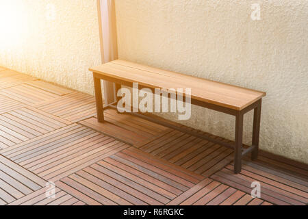 Lungo sedia in legno con cemento bianco parete Foto Stock