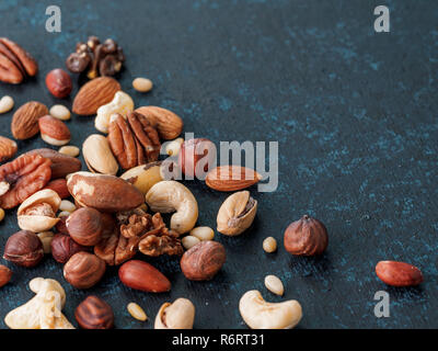 Mix di anacardi, pecan, pinoli, nocciole su blu Foto Stock
