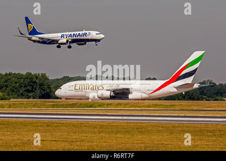 Una compagnia aerea Emirates Airbus A380 taxying per prendere il largo, mentre a Ryanair Boeing 737 terre overhead, all'Aeroporto di Manchester in Inghilterra. Foto Stock