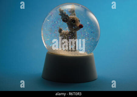 Le renne in una cupola di neve. Decorazione di natale. Isolato con sfondo blu. Foto Stock