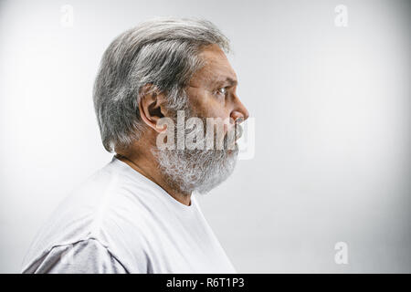 Il senior attraente man looking sorpresi isolato su bianco Foto Stock