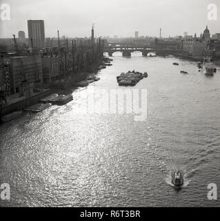 Degli anni Cinquanta, storico, un overhead vista guardando in direzione est fino al fiume Tamigi, Londra, Inghilterra,mostrando le banchine e gru che ancora rivestite il fiume in questo momento e le chiatte ormeggiate insieme nel mezzo del grande fiume. Foto Stock