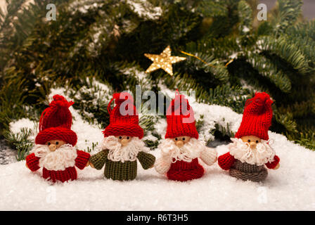 Un gruppo di quattro nani di natale in piedi nella neve di fronte alla foresta decorato Foto Stock