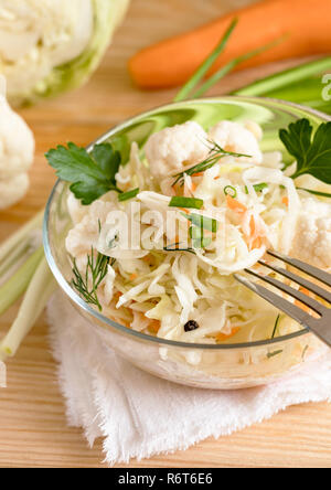 Insalata di crauti con le erbe in un recipiente di vetro è in piedi sulla tavola con forcella e ingredienti. Foto Stock