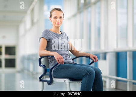 Paziente di sesso femminile, seduto in una sedia a rotelle per i pazienti di sensazione di non abbastanza bene da stand, in attesa di essere curato in un moderno ospedale (SHALLOW DOF dai toni di colore immagine) Foto Stock