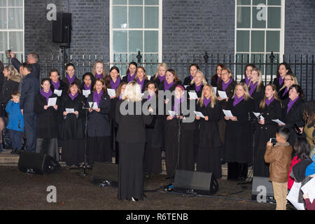 10 Downing Street, Londra, Regno Unito. 6 dicembre, 2018. British PM Theresa Maggio interruttori su albero di Natale luci a Downing Street con i membri dei militari mogli cori esecuzione di canti natalizi. Credito: Malcolm Park/Alamy Live News. Foto Stock