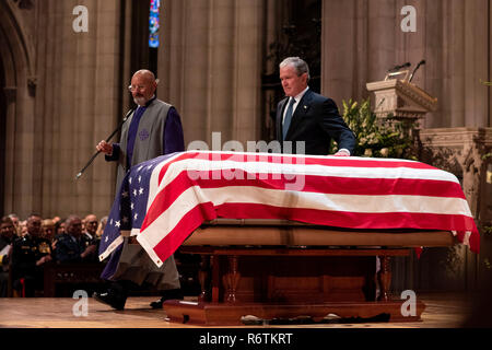 L ex Presidente George W Bush, arriva a toccare la bandiera drappeggiati scrigno di suo padre, ex Presidente George H.W. Bush dopo la consegna di un elogio al funerale di stato nella cattedrale nazionale il 5 dicembre 2018 a Washington, DC. Bush, la quarantunesima edizione del presidente, morì nella sua casa di Houston all'età 94 e verrà sepolto nella sua biblioteca presidenziale al Texas A&M University. Foto Stock