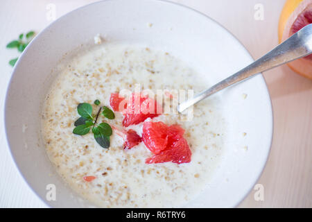 Dolce di farina di avena con fette di pompelmo rosso in un vaso di ceramica Foto Stock