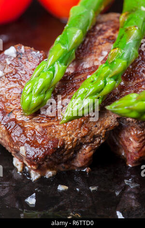 Bistecca di manzo e asparagi verdi in una padella Foto Stock