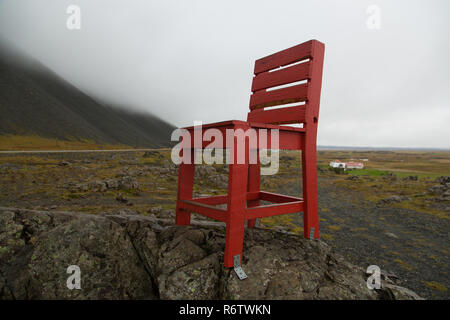 Un di legno grande sedia rossa su una roccia a mare vicino Eystrahorn, Est Islanda Foto Stock