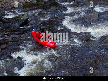 Uomo in rosso Kayak Going Down East Lyn fiume. Parco Nazionale di Exmoor, North Devon, Regno Unito. Foto Stock