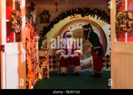 Babbo Natale seduto sulla sua poltrona e elfo aiutante Foto Stock