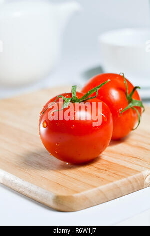 Rosso brillante i pomodori su un tagliere Foto Stock