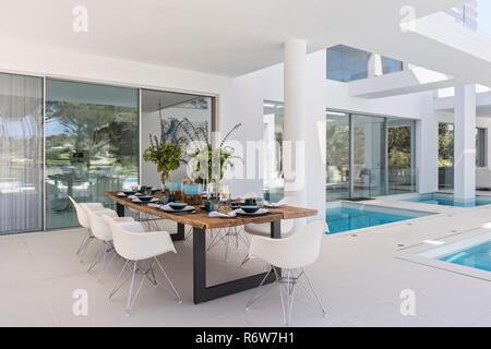 Tavolo da pranzo in legno e DSW tipo sedie per il pranzo sulla terrazza sahded di nuova costruzione di villa, Quinta do Lago Foto Stock