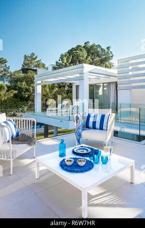 Blu e bianco striato cuscini poltrona con tavolo sulla terrazza in nuova costruzione di villa, Quinta do Lago Foto Stock