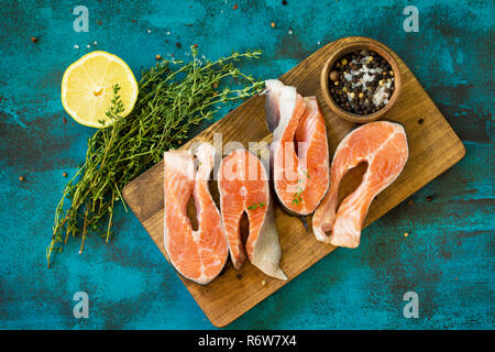 Pesce fresco. Raw Bistecca di salmone su un blu ardesia tabella. Vista superiore piatta sullo sfondo dei laici. Foto Stock