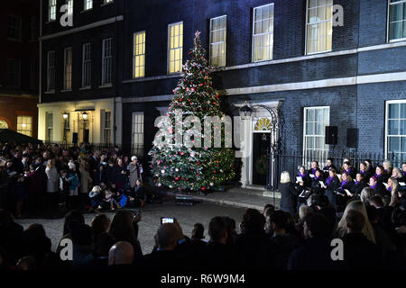 Carol cantanti di eseguire a Downing Street, Londra per l'albero di Natale interruttore luce on. Foto Stock