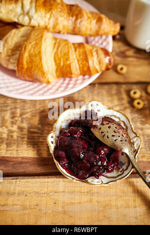 Vista dall'alto di una sana colazione con due cornetti e marmellata su un vecchio tavolo in legno Foto Stock