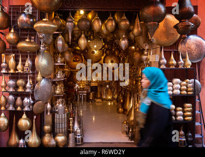 Il souk di Marrakech - un locale la donna araba camminare davanti a un negozio di artigianato, medina di Marrakesh, Marocco Africa del Nord Foto Stock