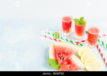 Tre bicchieri di succo di anguria con limone e menta su sfondo blu con spazio di copia Foto Stock