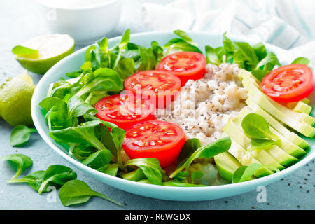 Farina di avena porridge con avocado e insalata di verdure fresche di pomodori e lattuga. Dieta sana prima colazione Foto Stock