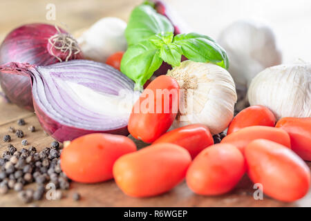 Fotografia di cibo.i pomodorini, cipolle, aglio, pepe nero e taglio fresco di foglie di basilico Pesto di ingredienti sul tavolo di legno.luminosi e vibranti veg. Foto Stock