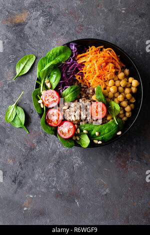 Un sano piatto vegetariano con il grano saraceno e insalata di verdure di ceci, kale, carote, pomodori freschi, foglie di spinaci e pinoli. Ciotola di Buddha. Balan Foto Stock