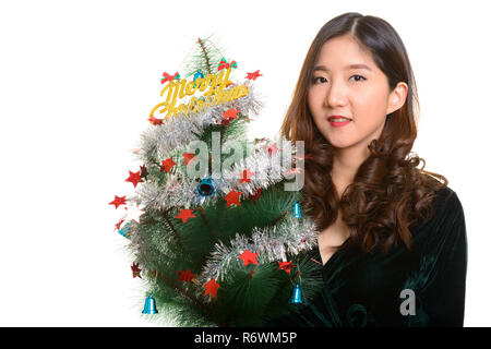 Felice giovane donna asiatica holding Merry Christmas tree Foto Stock