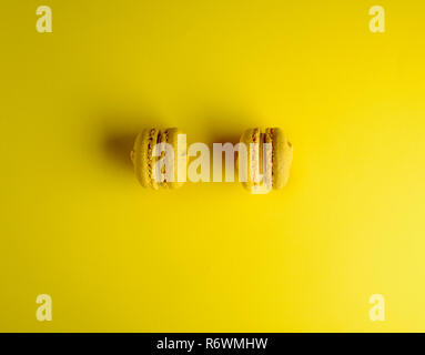 Due macarons giallo su sfondo giallo Foto Stock