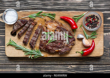 Bistecca di manzo con erbe e spezie su sfondo di legno. vista superiore Foto Stock