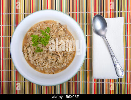 Ciotola di pollo in casa una zuppa di riso in una tazza bianca con cucchiaio e tovagliolo su un autunno di paglia colorata placemat. Uso perfetto per eventuali avanzi di turchia post hol Foto Stock