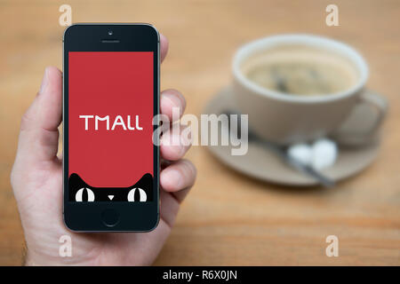 Un uomo guarda al suo iPhone che visualizza il logo Tmall (solo uso editoriale). Foto Stock