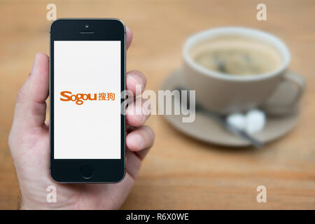 Un uomo guarda al suo iPhone che visualizza il logo di Sogou (solo uso editoriale). Foto Stock