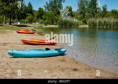 Kayak allineati su una spiaggia in un piccolo stagno Foto Stock