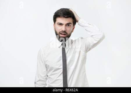 Bel uomo spagnolo con la barba di graffiare la testa mentre è perplesso o clueless Foto Stock