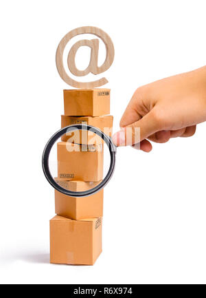 Lente di ingrandimento è guardando la torre di scatole di cartone e un simbolo di posta sulla sommità. concetto di vendita online, shopping e lo shopping online. Realiza Foto Stock