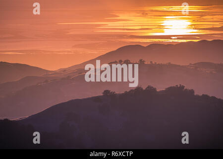 Splendide colline immerso nella luce del tramonto; il sole al tramonto riflesso nell'acqua della baia di San Francisco in background; vista da Mt ha Foto Stock